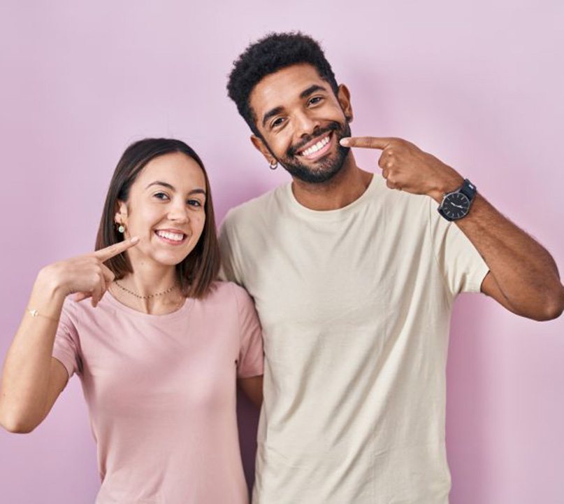 Happy young couple pointing at their teeth