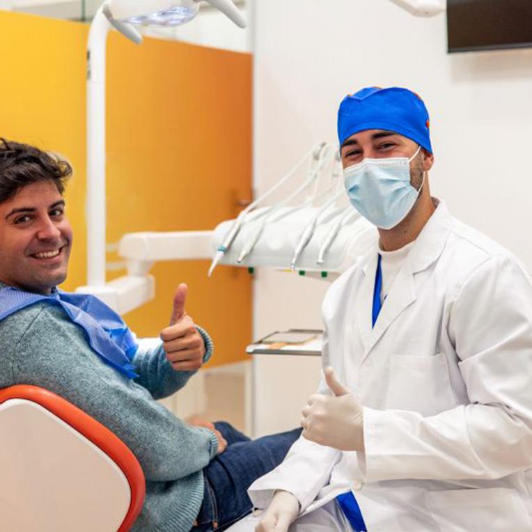 Patient posing with dentist, making thumbs-up gesture