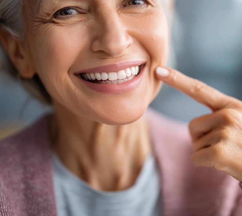Happy older woman pointing at her teeth