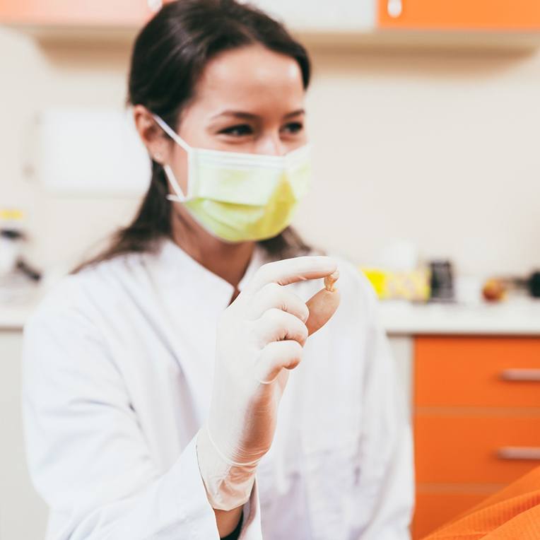 Patient smiling while dental team member holds her extracted tooth