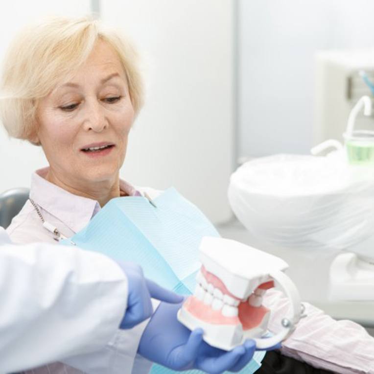 Dentist showing patient an implant denture model