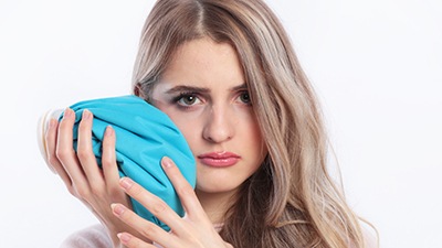 woman putting ice pack on cheek 