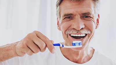 man brushing teeth after getting dental implants