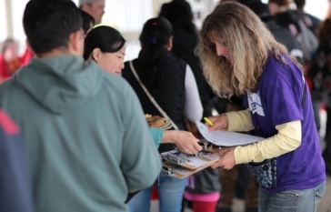 People signing clipboard at community event