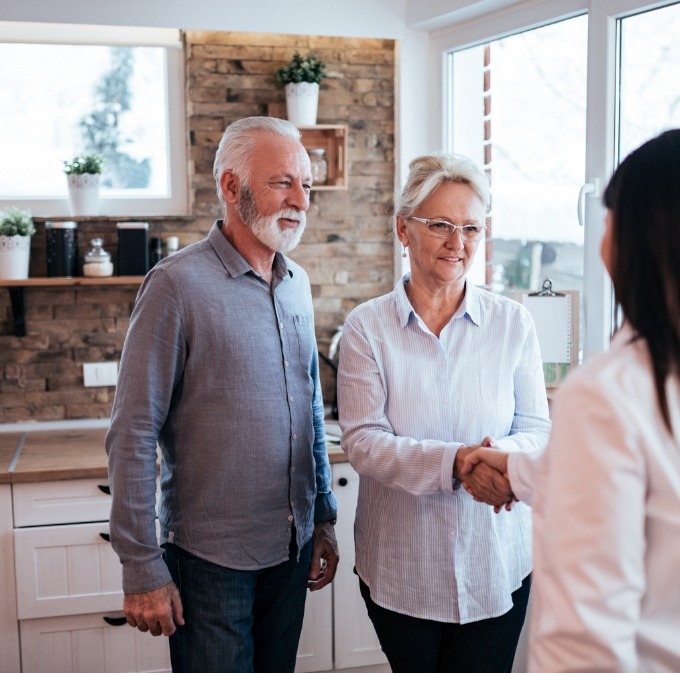 Senior man and woman shaking hands with woman in their kitchen