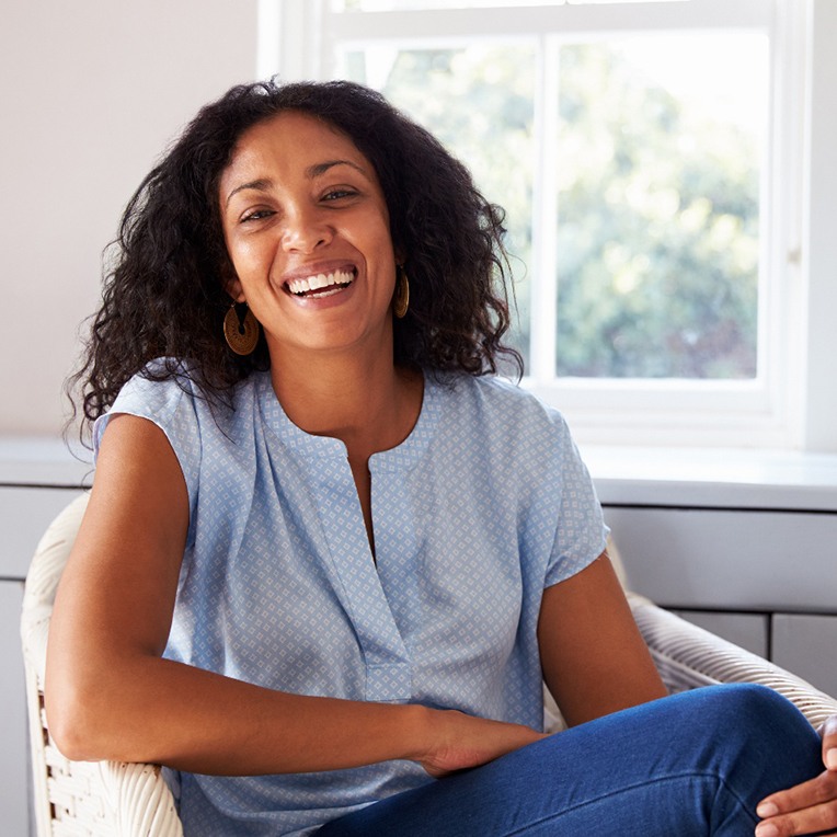 Happy middle-aged woman sitting in chair at home