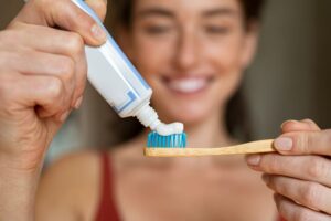 Smiling woman putting toothpaste on her toothbrush