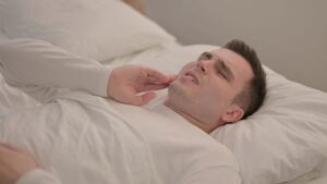 Man lying in bed, suffering from a toothache