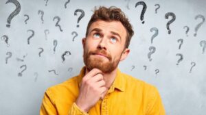 Man wearing thoughtful expression, with question marks around his head 