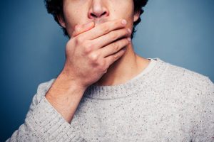 Bottom half of man’s face as he covers his mouth